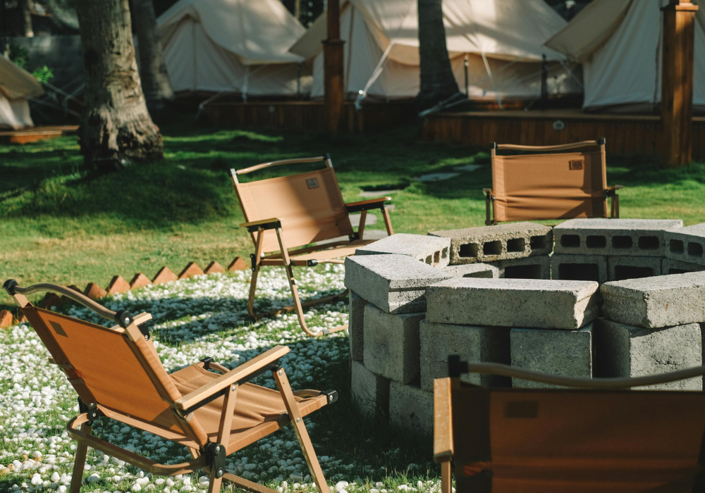 A glamping setup with a fire pit and deck chairs